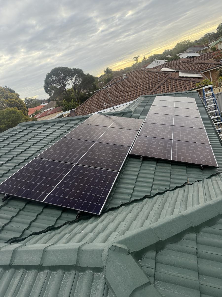 Solar panels on a green tiled roof at sunset