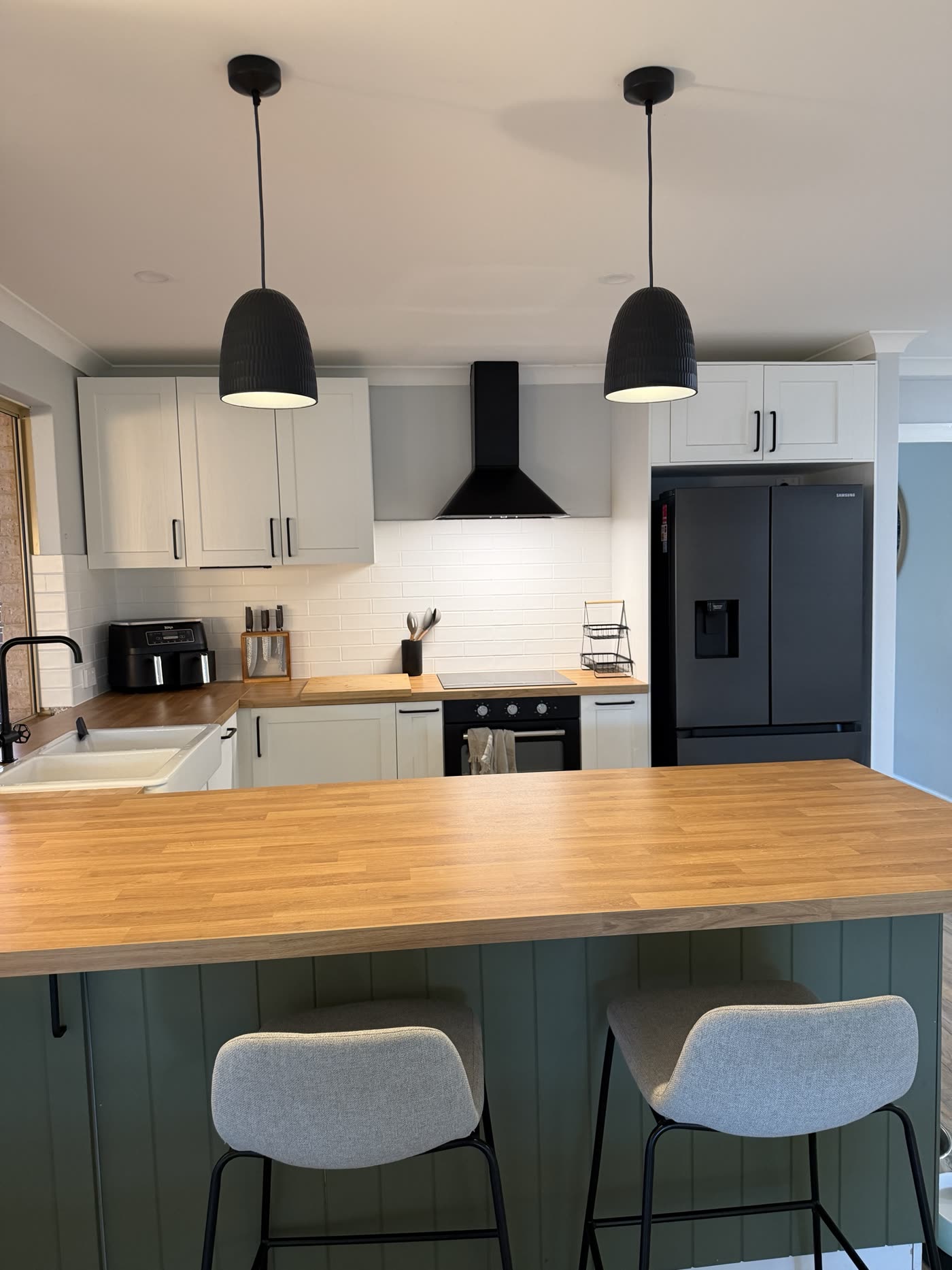 Kitchen with two black dome pendant lights over a timber benchtop