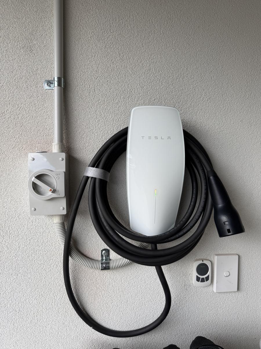 Wall-mounted home EV charger with coiled cable, isolator and conduit