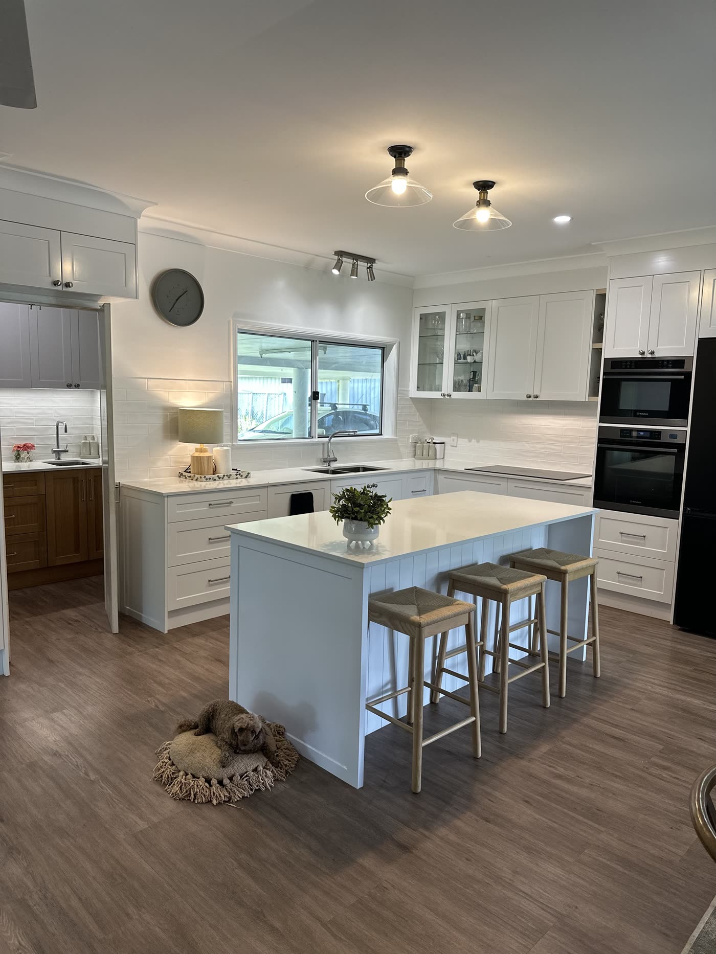 Shaker-style kitchen with glass pendant lights, downlights and a track light over the island
