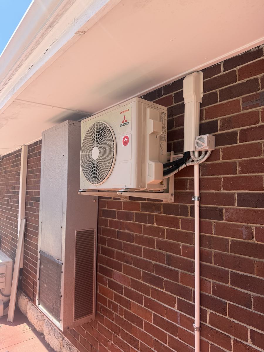 Mitsubishi outdoor air conditioning unit on a wall bracket with isolator and conduit