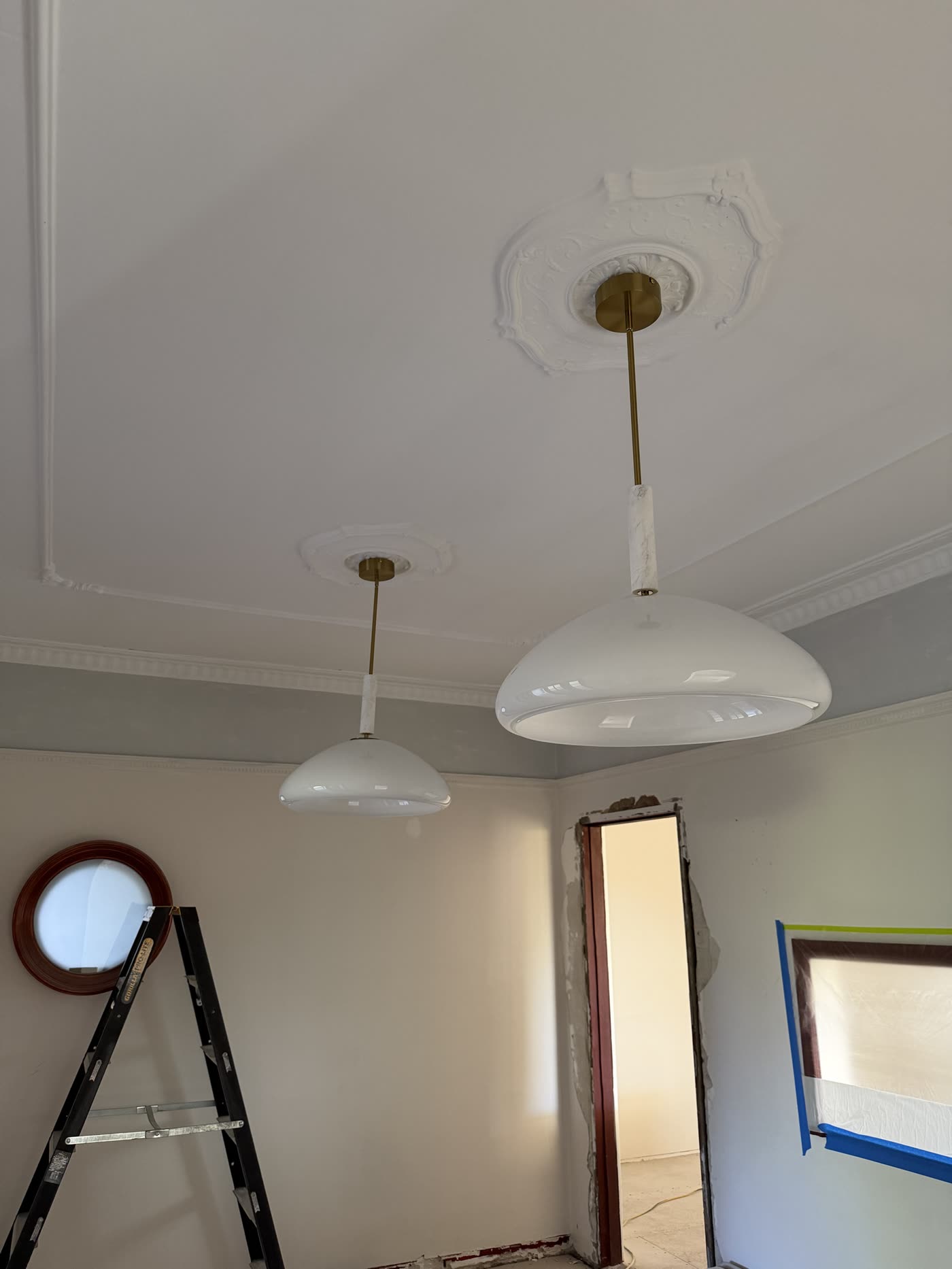 Two white glass pendant lights with brass fittings hung from ornate ceiling roses