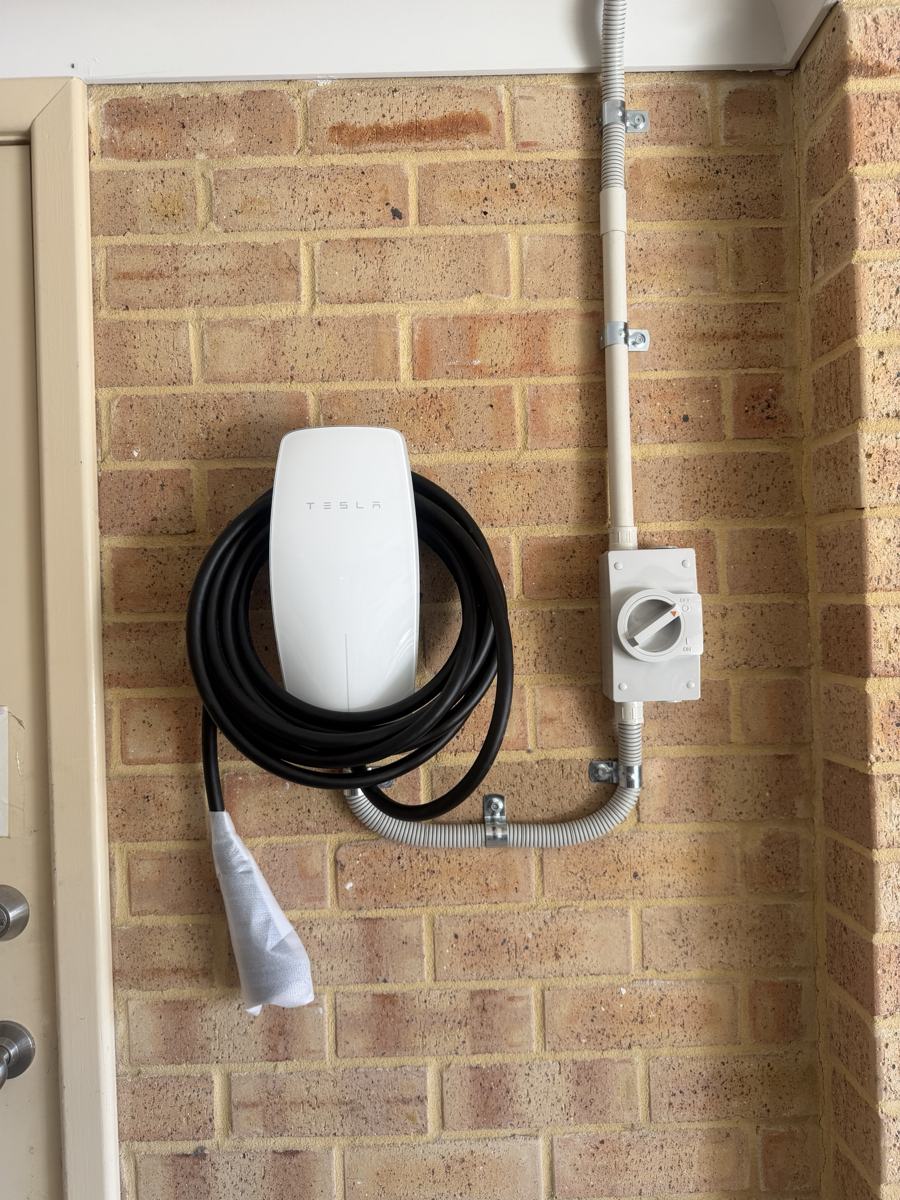 Wall-mounted home EV charger with isolator and conduit on a brick wall