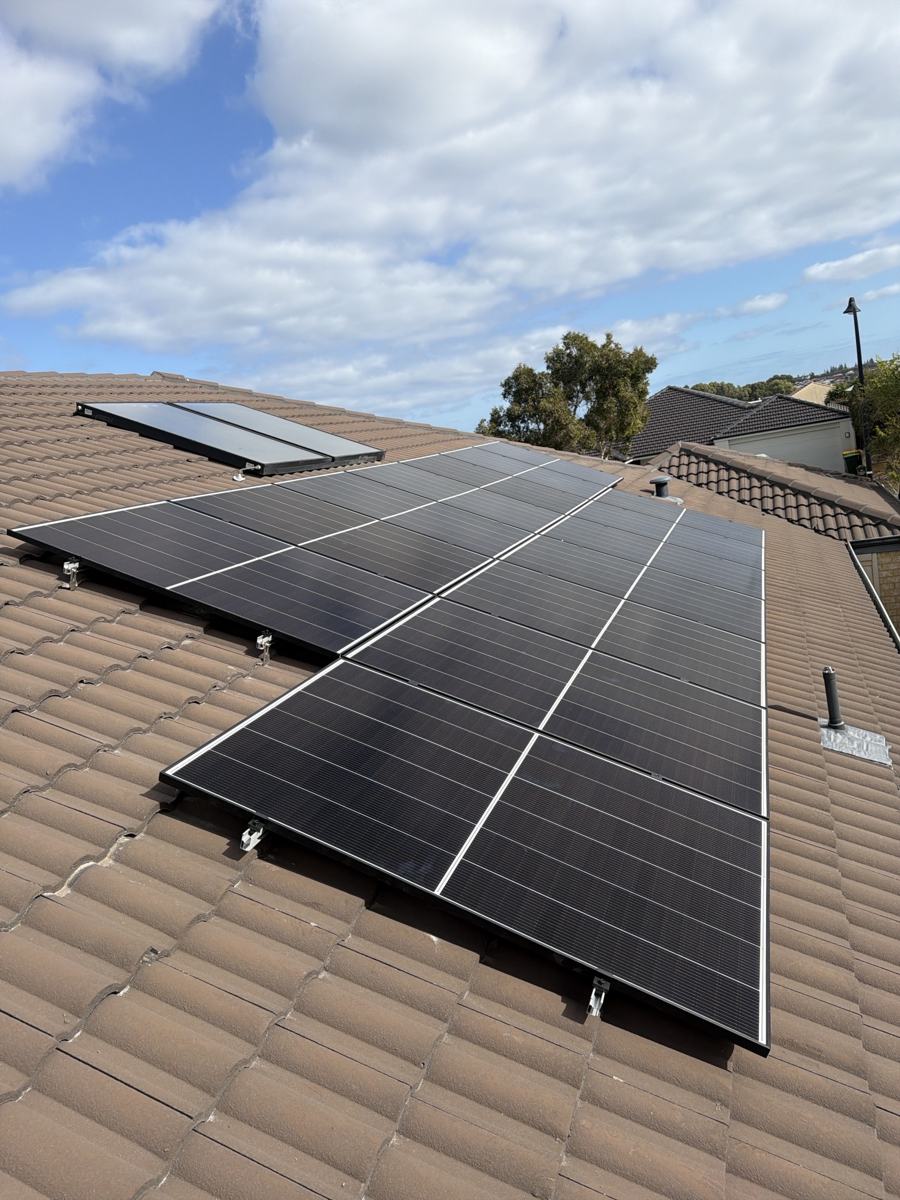 Solar array on a brown tiled roof beside a solar hot water panel